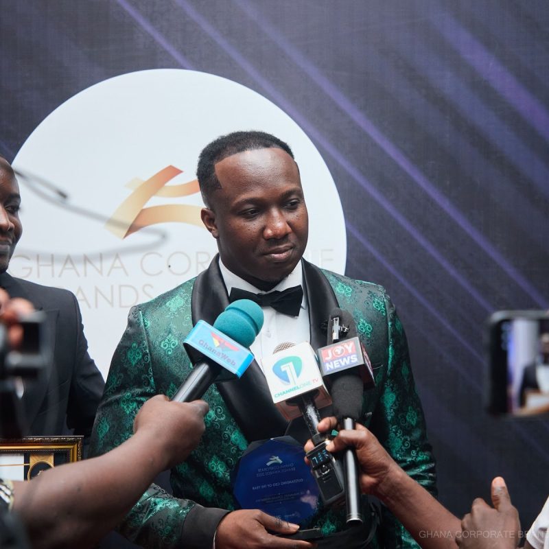 A guest interviewed in front of the Ghana Corporate Brands Awards mark